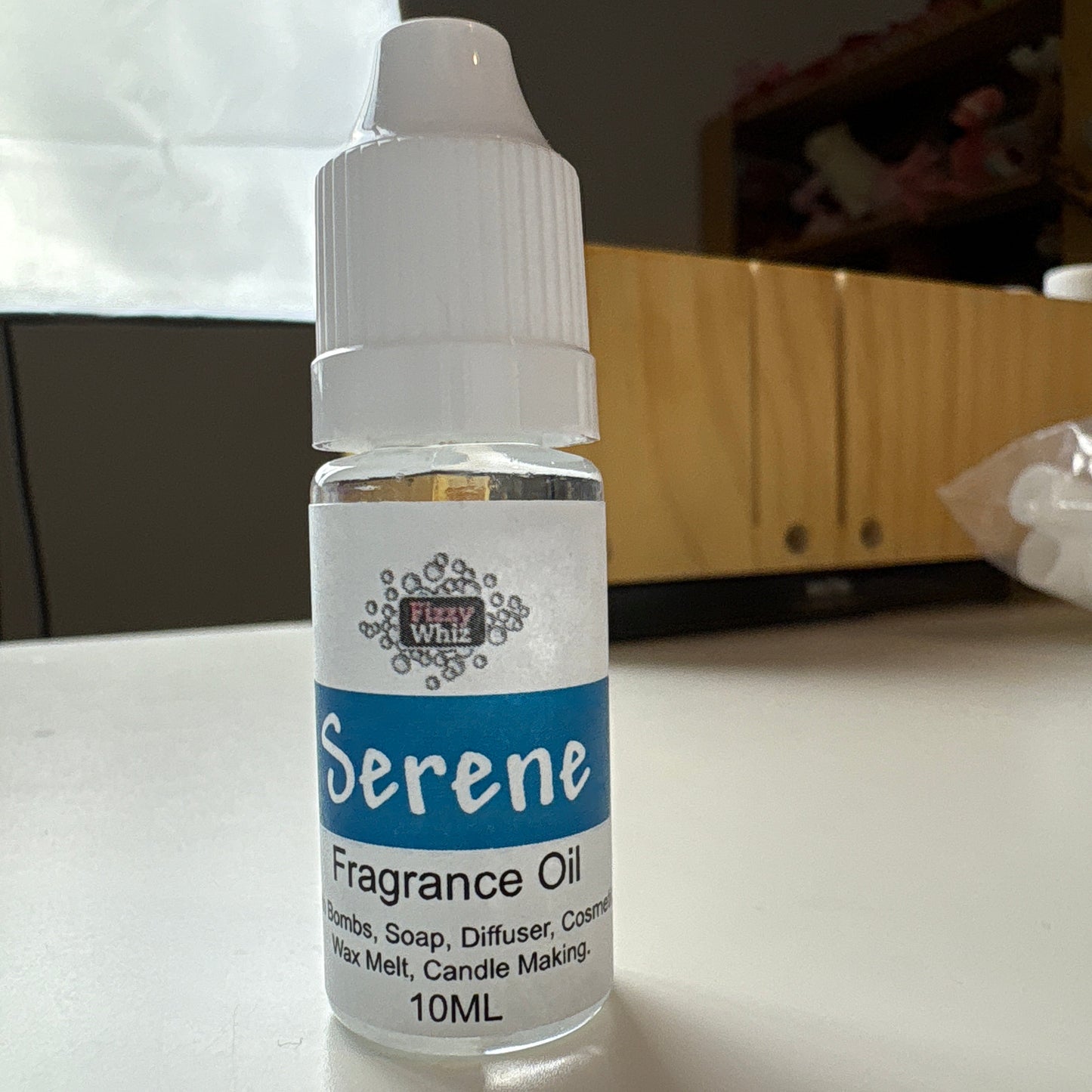 Serene brand fragrance oil bottle on a white surface with a blurred background