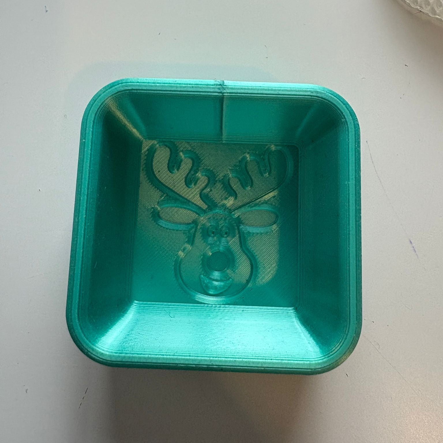 Green plastic container with a deer design on a white surface